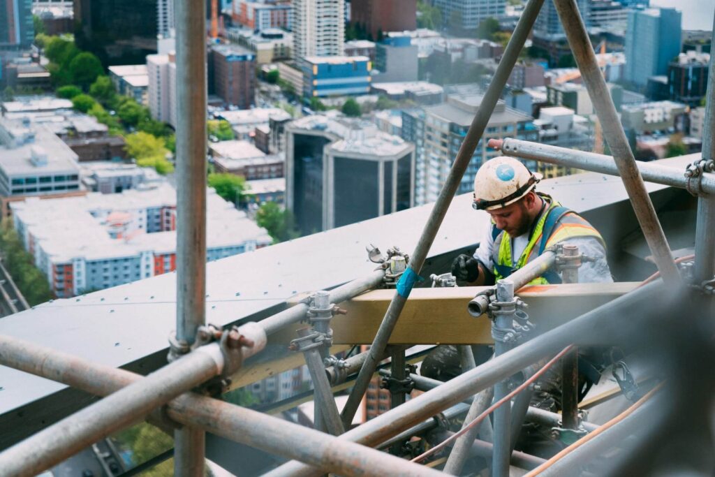 High-rise construction worker performing structural inspection on scaffolding for building safety assessment