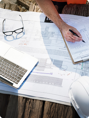 Engineering blueprints with laptop and safety helmet for building inspection planning and structural design review